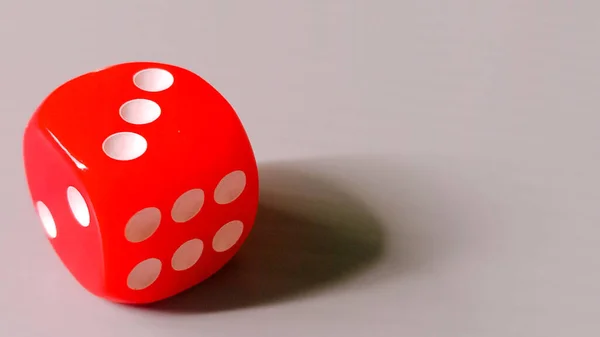 Üç numarayı gösteren canlı kırmızı zarlar, tarafsız bir arkaplanda dinleniyor..