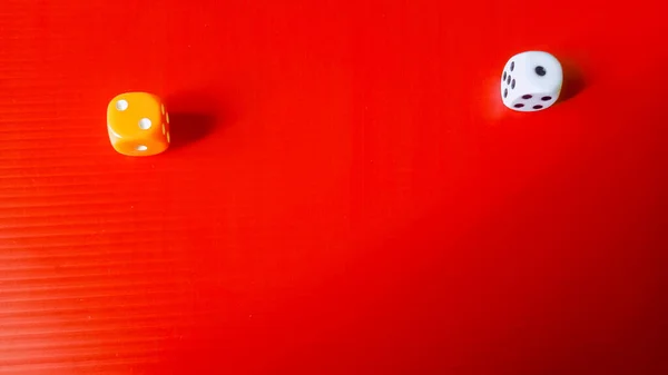 Bu altı kenarlı iki zarın canlı kırmızı bir yüzey üzerinde yan yana duran makro bir fotoğrafı..