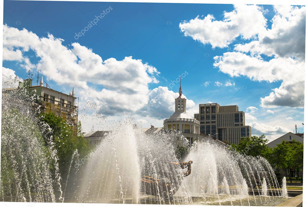 Summer view of the Dnipro city. Beautiful fountain on the background of a buildings, blue sky and white clouds. (Dnepropetrovsk, Dnepr), Ukraine