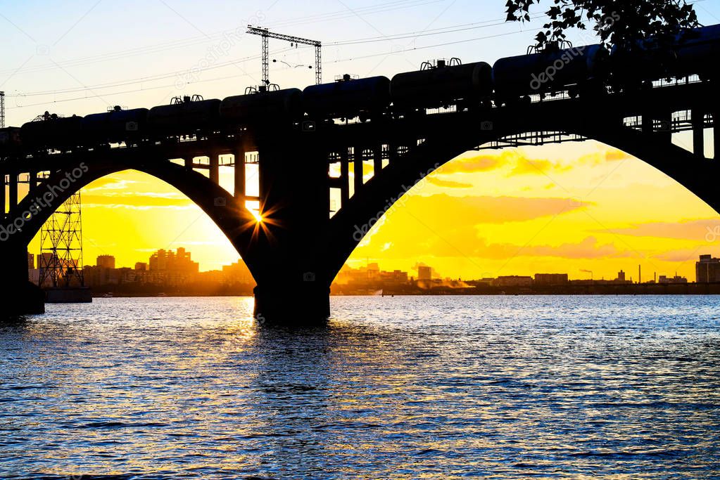 Silhouette of a beautiful arched railway bridge and wagons on the Dnieper river at sunset. Dnipropetrovsk (Dnepr, Dnipro, Dnepropetrovsk) Ukraine.