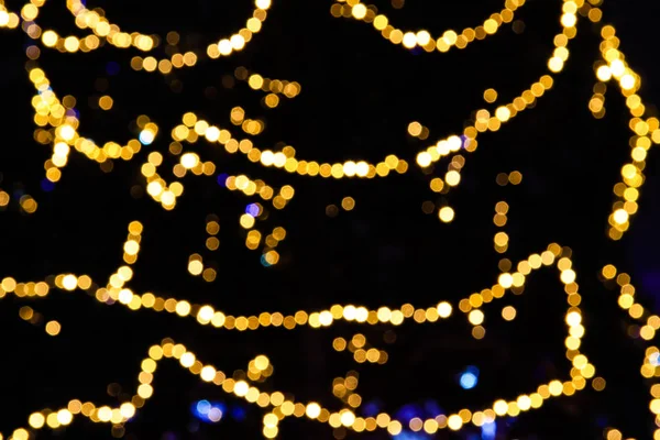 Blurred yellow lights of Christmas lights on a Christmas tree, abstract bokeh, defocused background.