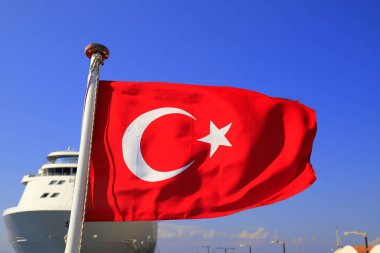 Kırmızı bayrak, Türkiye Milli bir yarım ay ve mavi gökyüzü ve bir büyük beyaz okyanus gemisi, Türk sembolü bir bayrak direğine çırpınan karşı bir yıldız ile