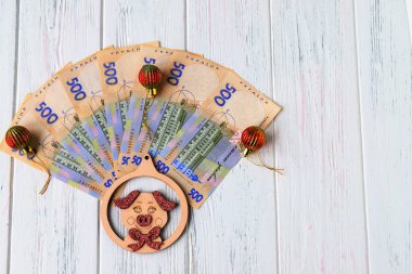 Ukraynalı hryvnia oyuncak domuz, 2019 sembolü ve eski bir ışık, ahşap arka plan üzerinde kırmızı Noel süsleri banknotlar 500 hryvnia. Ukrayna
