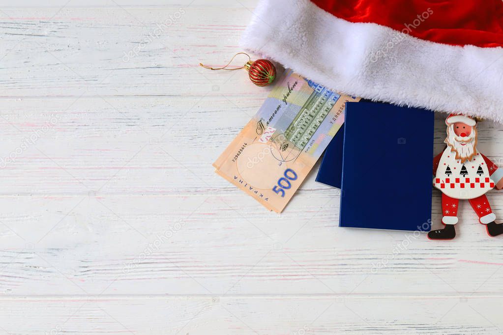 Ukrainian hryvna, banknotes 500 hryvnia, with red Santa Claus hat and blue passport on an old light, wooden background. Christmas, New Year and travel  concept. Ukraine. gryvnia, gryvna, grivna, grivnia, hrivnia,hrivna
