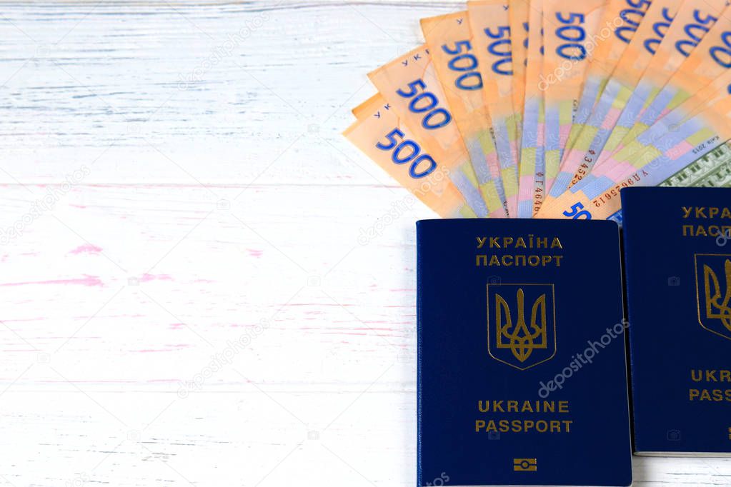 Ukrainian hryvna, banknotes 500 hryvnia, with blue passport on an old light, wooden background. Christmas, New Year, tourism,  and travel  concept.  Ukraine