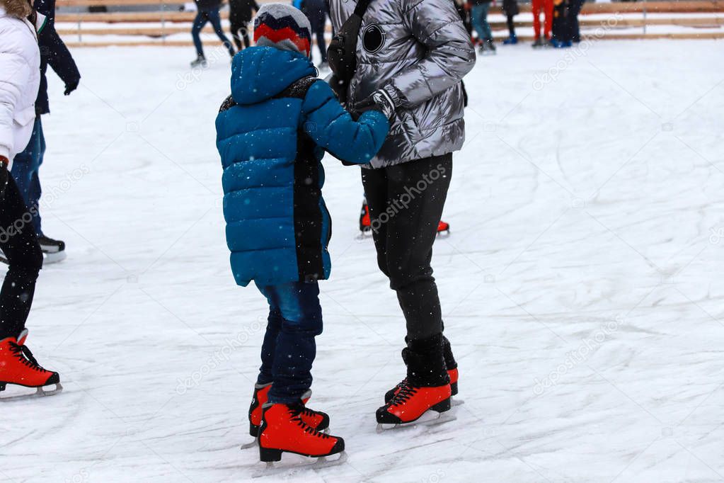 Children's rink. The instructor teaches the teenager boy to skate. Active family sport during the winter holidays and the cold season. School sports clubs