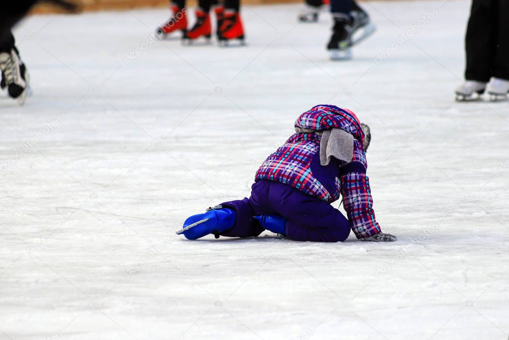 Children s skate rink. A little boy skates and falls on the ice in winter  Active family sport during the winter holidays and the cold season. School sports clubs