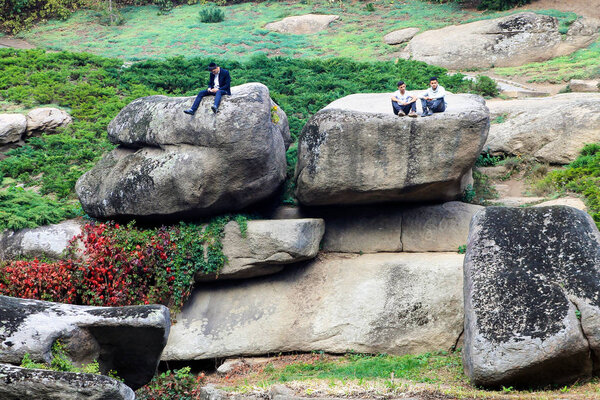 Uman, Ukraine, 22 09 2018. Young  boys, Hassidic Jews sit on big stones in a park in the Ukrainian city of Uman during the Jewish New Year