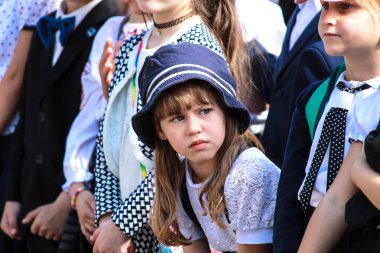 Dnipro City, Ukrayna, 25.05 2018.Mavi şapkalı yorgun bir kız birinci sınıf bir okul tatili sırasında bir gösteri izliyor.