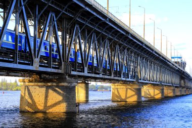 Yolcu treni iki seviyeli bir köprü boyunca geziyor ve bahar aylarında Dnipro kentinde Dinyeper Nehri 'nin karşısında bir demiryolu var. Dnepropetrovsk, Ukrayna. taşıma ve altyapı