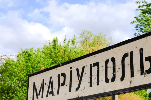 Sinal de estrada com a inscrição em Mariupol ucraniana, cidade da região de Donetsk, perfurado por balas, guerra ucraniana, conflito Leste da Ucrânia — Fotografia de Stock