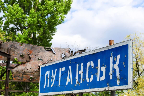 Blaues Straßenschild mit der Aufschrift im ukrainischen Lugansk, von Kugeln durchlöchert während des Krieges im Donbass, Konflikt Ostukraine, ukrainischer Krieg — Stockfoto