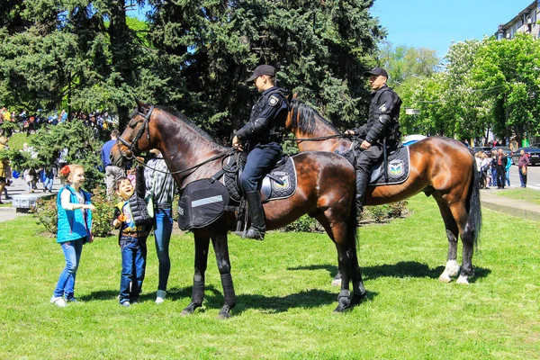 Dnipro ， Dnepropetrovsk， 乌克兰， 2018年5月9日.骑在马背上的巡逻警察在公共活动中保护公共秩序。孩子们和马一起玩 — 图库照片