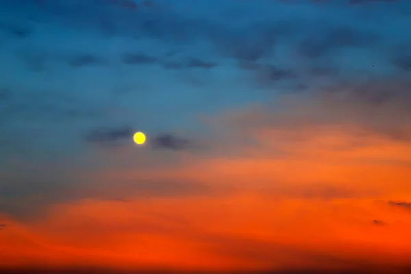 Picturesque Full moon on a background of beautiful blue and red clouds. Clouds at sunset, sunrise during the full moon. Cloud background, text space.