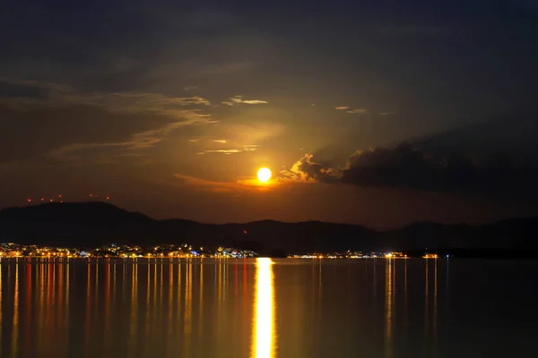 Picturesque night sea, river, ocean landscape. A beautiful full moon over the sea bay, the light of the moon and lanterns reflected on the calm water. Sibenik, Croatia