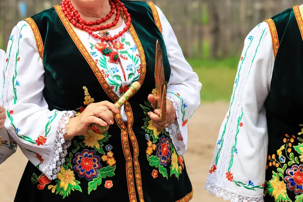 Uma mulher idosa em uma camisa ucraniana bordada toca instrumentos folclóricos no festival étnico em Petrykivka, região de Dnipropetrovsk, verão, Ucrânia — Fotografia de Stock