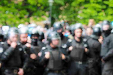 Bir toplu etkinlikte polisin bulanık görüntüsü. Kasklı polis mitingdeki emri koruyor. Sokakta ki gösteride polisler