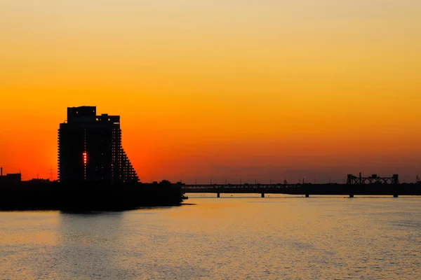 Silhueta de um arranha-céu e uma ponte em um contexto de um belo pôr-do-sol sobre um rio. Paisagem da cidade no verão, primavera, outono. Dnepropetrovsk, Dnipro, Ucrânia, Rio Dnieper — Fotografia de Stock