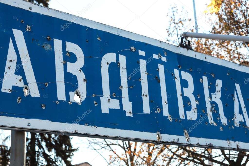 Road sign with the inscription in Ukrainian Avdiivka, town of Donetsk region, broken by bullets during the war in the Donbass, Ukraine. Armed conflict east of Ukraine, Ukrainian war