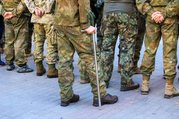 A wounded soldier of the Ukrainian army stands with a crutch near the formation of war veterans, Defender Ukraine Day. Armed forces of Ukraine, Ukrainian war — Stock Photo, Image