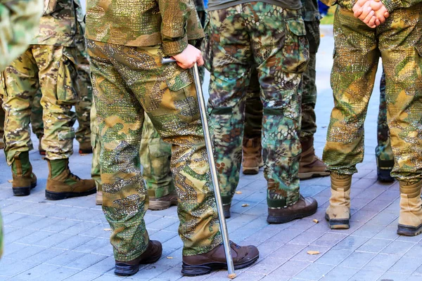 Ένας τραυματισμένος στρατιώτης του ουκρανικού στρατού με στολή στέκεται με ένα δεκανίκι κοντά στο σχηματισμό βετεράνων πολέμου, την ημέρα του υπερασπιστή της Ουκρανίας. Ένοπλες δυνάμεις της Ουκρανίας, πόλεμος της Ουκρανίας — Φωτογραφία Αρχείου