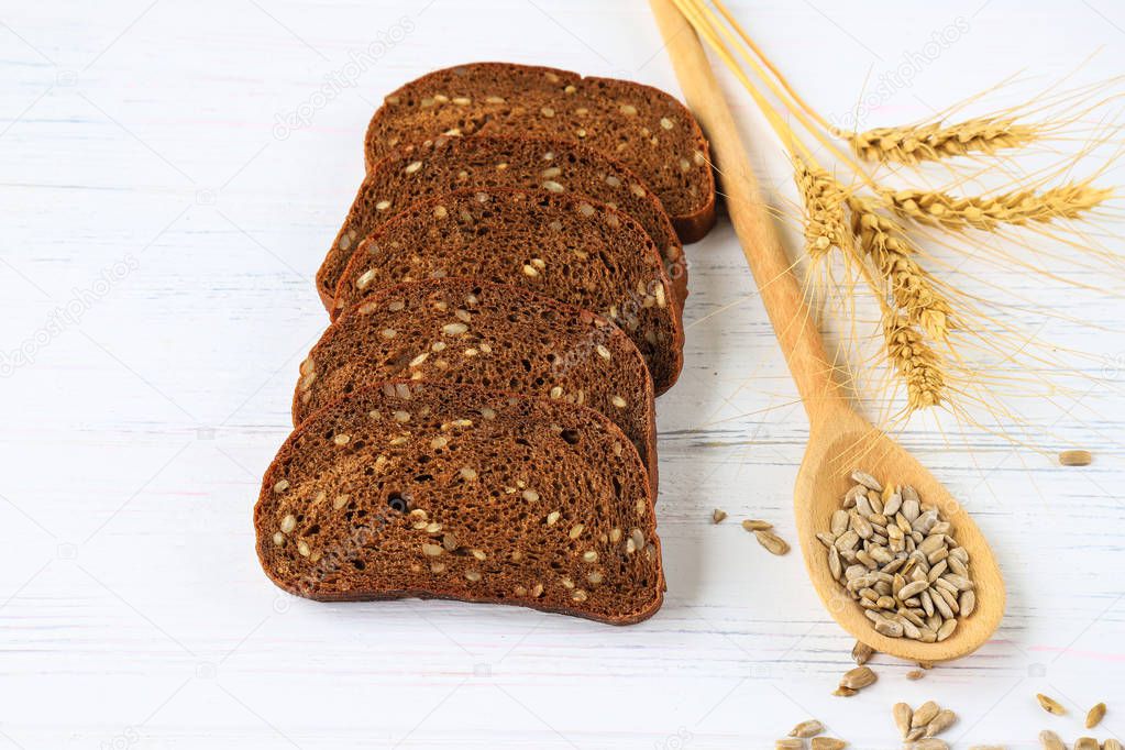 Rustic breakfast on a wooden background - sliced bread with seeds, seeds on a spoon, ears of wheat