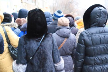 Kışın ve sonbaharda sokaktaki bir sürü insan. Mağazanın yakınında ceketli ve kürklü insanlar var. Alıcılar Kara Cuma günü alışveriş merkezine giriyor. Kış indirimi, indirimler. Meşgul insanlar