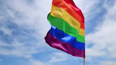 Mavi gökyüzüne el sallayan LGBT örgütünün gerçekçi gökkuşağı bayrağı. Lezbiyenler, geyler, biseksüeller ve transseksüeller için LGBT gurur bayrakları 