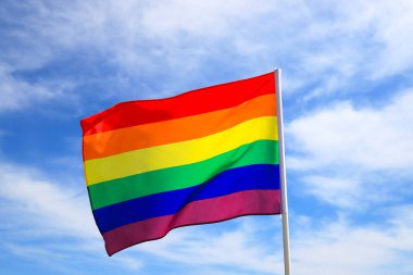 Mavi gökyüzüne el sallayan LGBT örgütünün gerçekçi gökkuşağı bayrağı. Lezbiyenler, geyler, biseksüeller ve transseksüeller için LGBT gurur bayrakları.