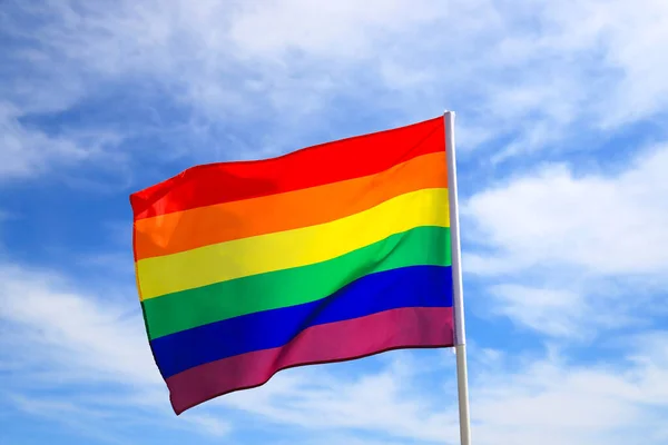Mavi gökyüzüne el sallayan LGBT örgütünün gerçekçi gökkuşağı bayrağı. Lezbiyenler, geyler, biseksüeller ve transseksüeller için LGBT gurur bayrakları.