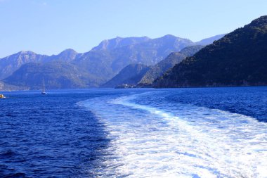 Türkiye 'de Bodrum ve Marmaris yakınlarındaki resim gibi deniz manzarası, suda bir tekneden bir iz, dalgalar, kaynayan bir deniz. Körfezin etrafındaki dağlar ve tepeler, yazlık manzaralar.