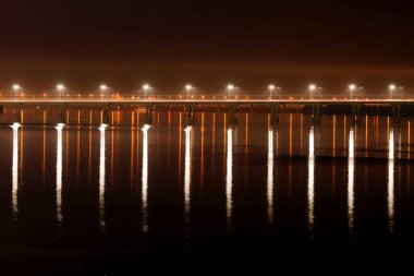 Güzel fenerlerle dolu gece köprüsü Dinyeper Nehri 'ndeki suya yansıyor. Büyük bir şehirde akşam nehir manzarası. Dnepropetrovsk, Dnipro şehri, Ukrayna.