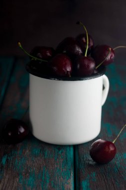 Kiraz rustik ahşap masa üzerinde teneke Kupası'nda. Tonda fotoğraf.