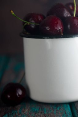 Kiraz rustik ahşap masa üzerinde teneke Kupası'nda. Tonda fotoğraf.