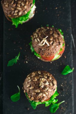 Yeşil salata, domates, salatalık ve beton masa üzerine krem peynir sandviç.