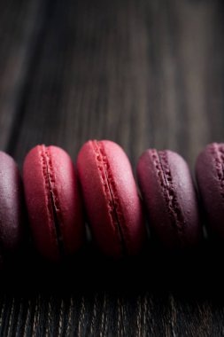 Grup macarons çilek, krema, çikolata ve yaban mersini yaptı. Rustik fotoğraf. Tonda.