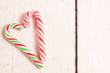 Baston şekerler Beyaz ahşap rustik masa üzerinde kalp şeklinde.