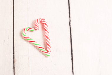 Baston şekerler Beyaz ahşap rustik masa üzerinde kalp şeklinde.