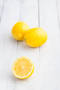 Beyaz ahşap masa üzerinde üç limon. Parlak fotoğraf.