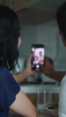 Genç bir çift yemek sırasında cep telefonlarıyla video görüşmesi yapıyor.