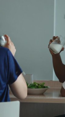 Çift besleyici salata paylaşır, süt döker, mutfakta birlikte yemek yer.