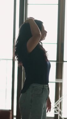 Geniş pencerenin yanında dans eden zarif bale sanatçısı, akışkan hareketi ifade ediyor - 4K Yatay