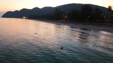 Güneş Aao thung Makham sahilinde sessizce batarken iki kişi balık tutuyor - 4K yatay