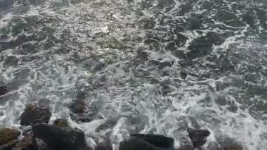 Dalga, denizin kıyısındaki kayalara sıçrıyor ve sıçrıyor. Dalgalar sıçrıyor ve sıçrıyor..