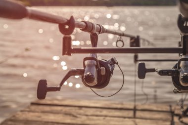 Ahşap iskelede bir balık tutacağının üzerinde olta kamışı. Balık tutma günü