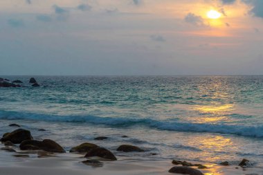 Denizde sakin bir gün batımı. Günbatımı arka planında turkuaz deniz.
