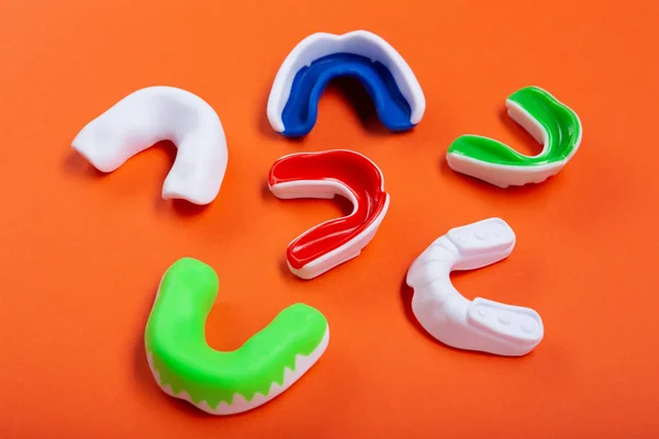 Lots of boxing protective mouthguards on orange background, concept — Stock Photo, Image