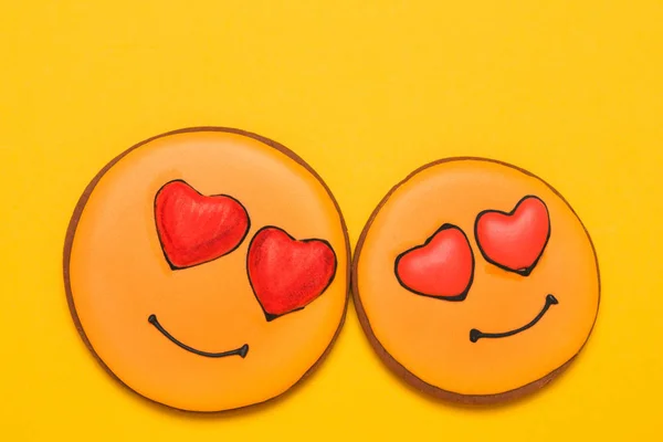 Два жовтих печива у формі посмішок, з очима у формі сердець, на жовтому тлі, концепція любові та відносин — стокове фото