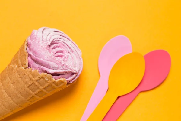 Waffle cone med dessert på en gul bakgrund och tre flerfärgad skedar i närheten, minimal holiday koncept — Stockfoto