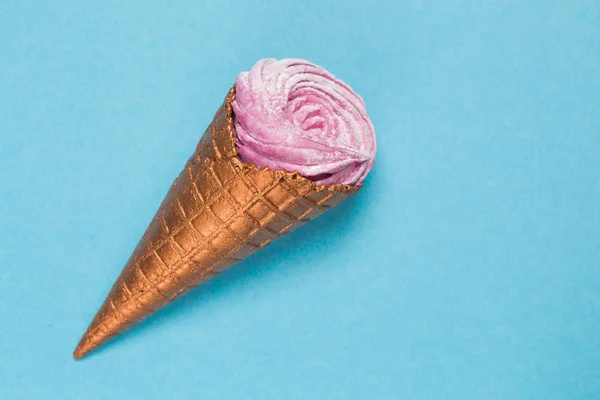Golden waffle cone with dessert on a blue background, minimal concept, close-up — Stock Photo, Image
